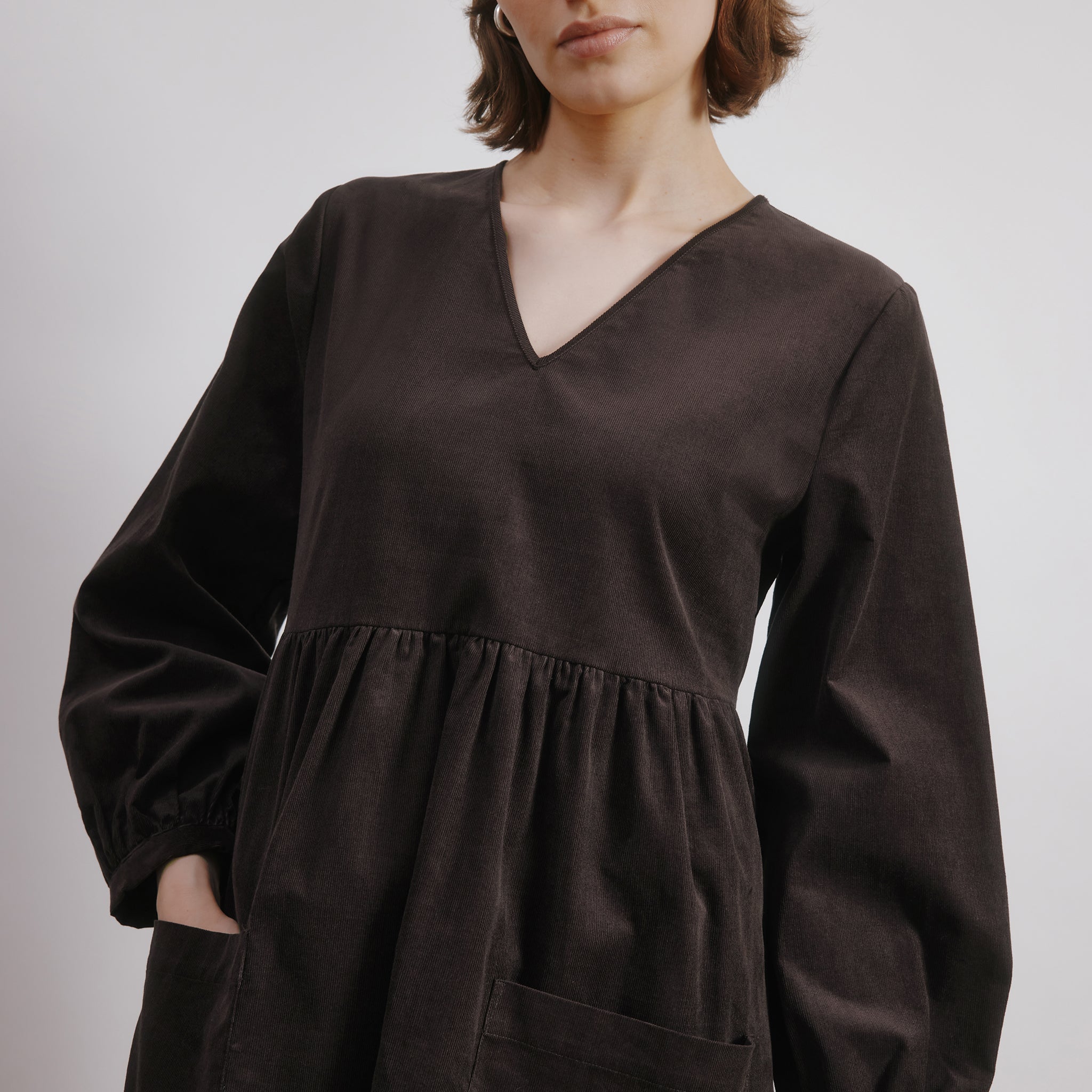 side view of brown cord mini dress with blouson sleeves and organic cotton fabric