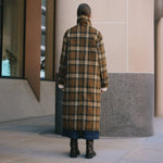 Oversized check wool coat in black, cream, and tan with a funnel neck design, relaxed fit and long winter silhouette.
