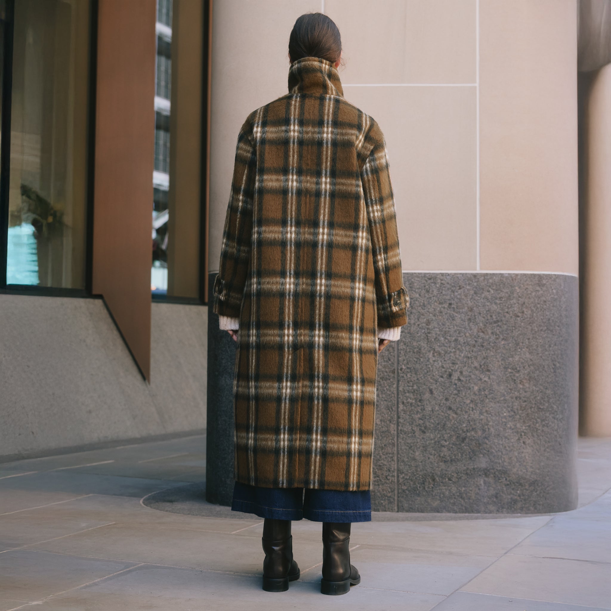 Oversized check wool coat in black, cream, and tan with a funnel neck design, relaxed fit and long winter silhouette.