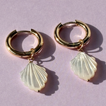 Close-up of gold plated hoop earrings featuring smooth mother of pearl accents.