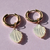 Close-up of gold plated hoop earrings featuring smooth mother of pearl accents.