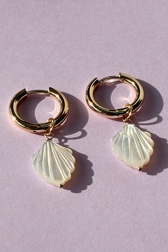Close-up of gold plated hoop earrings featuring smooth mother of pearl accents.