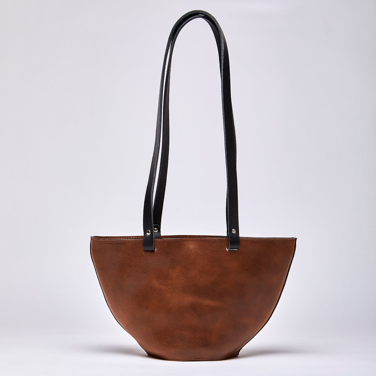 Close-up of brown leather handbag strap with detailed stitching on upcycled leather bag