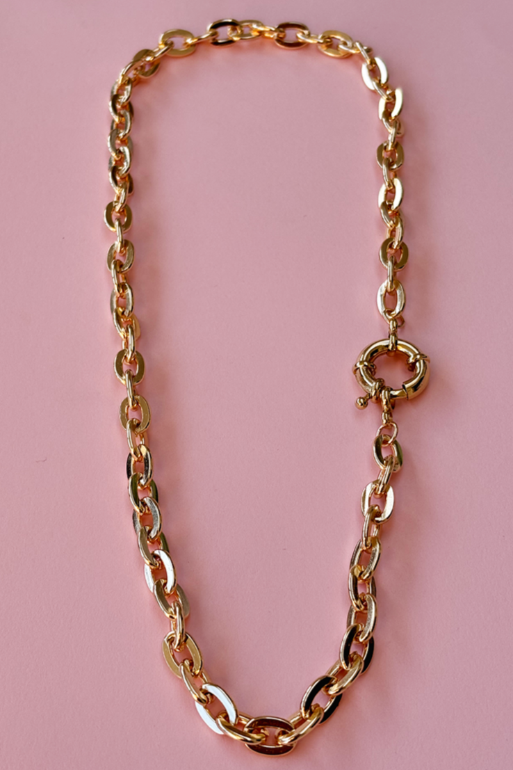 Model wearing a gold plated chunky chain necklace with a prominent front clasp.