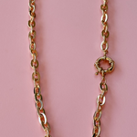 Model wearing a gold plated chunky chain necklace with a prominent front clasp.