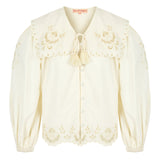 Close-up of scalloped edge on a button up white blouse with balloon sleeves and tie neck.