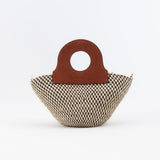 Handwoven basket bag featuring sturdy upcycled leather handles.