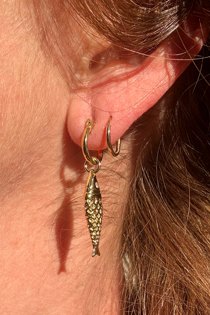 Close-up of gold plated mini hoops highlighting smooth polished finish.