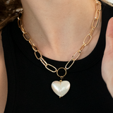 Close-up of mother of pearl pendant on a gold plated chunky chain necklace.