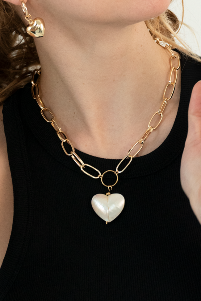 Close-up of mother of pearl pendant on a gold plated chunky chain necklace.