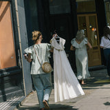 Model wearing a high neck blouse with ruffle sleeves and button up cotton shirt.