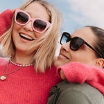 Model wearing black sunglasses with tinted coloured lenses in outdoor light.