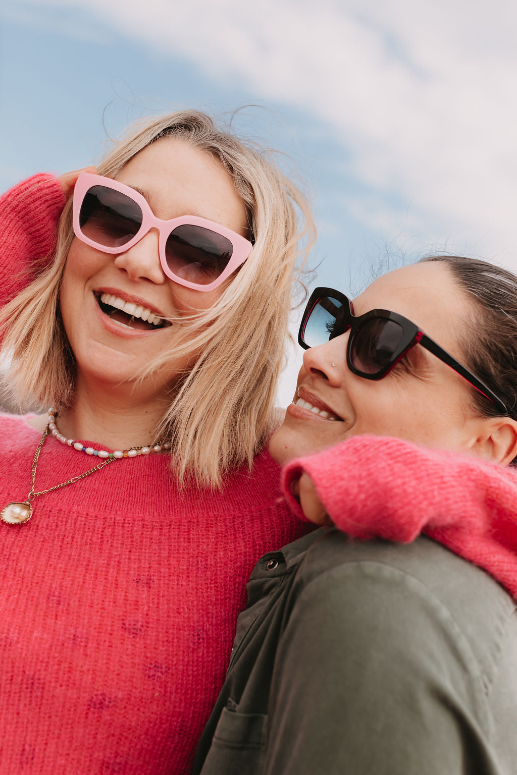 Model wearing black sunglasses with tinted coloured lenses in outdoor light.
