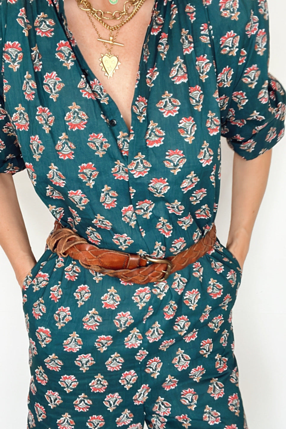 Fashion shot of floral dark green jumpsuit with balloon sleeves, V neck, and button front.