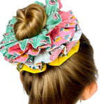 Close-up of a green floral scrunchie showing intricate flower patterns and texture.