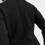 Model wearing a minimal black cocoon sleeve knit jumper, showing off compact knit fabric and voluminous sleeves, perfect for transitional knitwear collections.