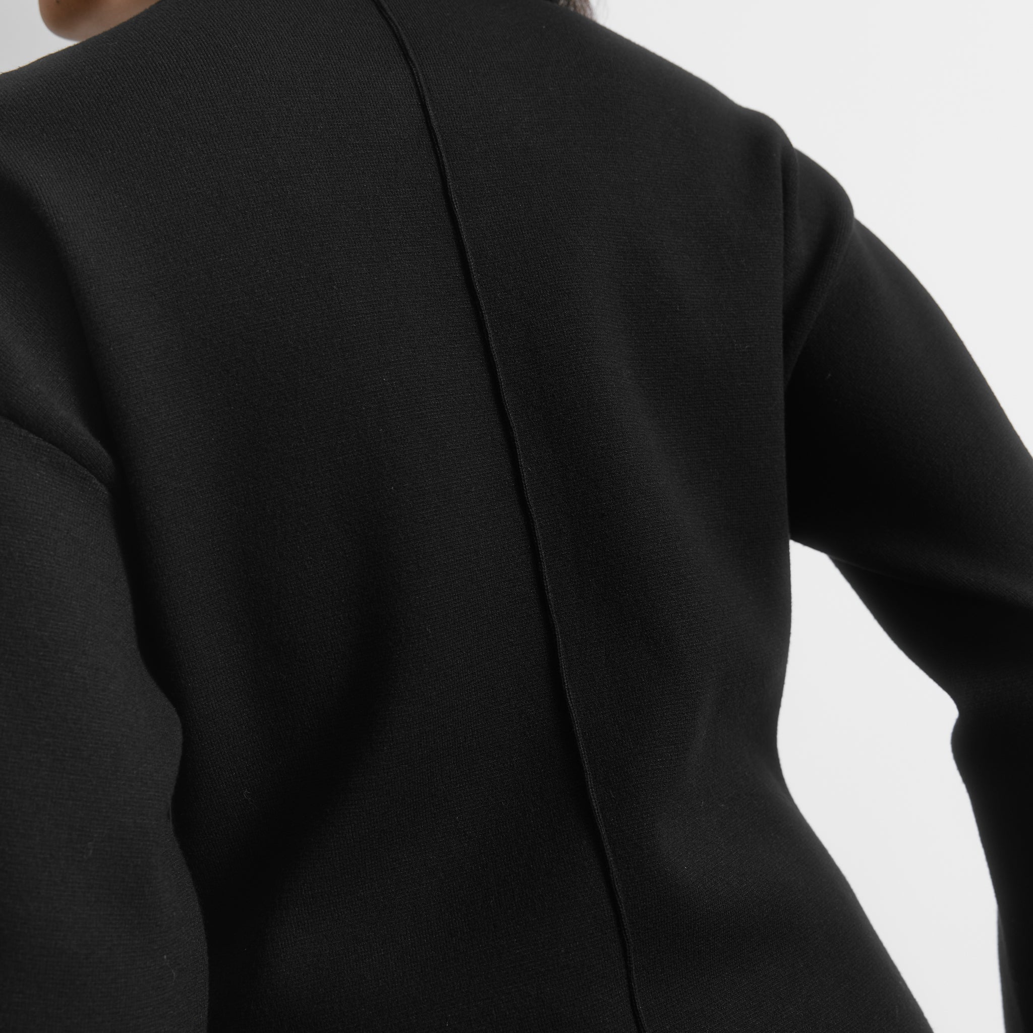 Model wearing a minimal black cocoon sleeve knit jumper, showing off compact knit fabric and voluminous sleeves, perfect for transitional knitwear collections.