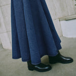 Close-up of organic cotton indigo denim skirt fabric with visible contrast stitching and basque waist design, showcasing ethical craftsmanship.