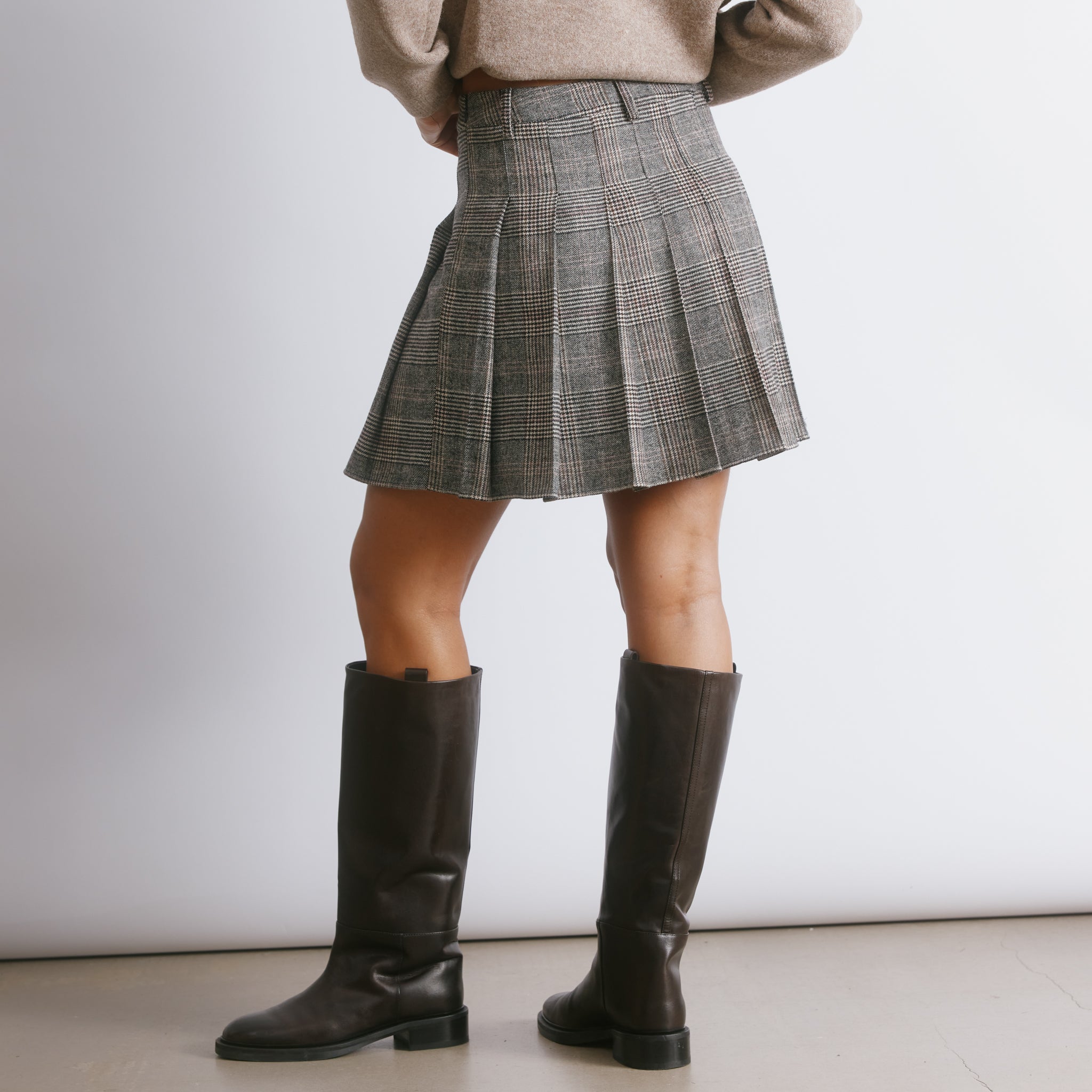 Tailored check mini skirt with structured pleats and a classic pelmet silhouette for a modern heritage look.  