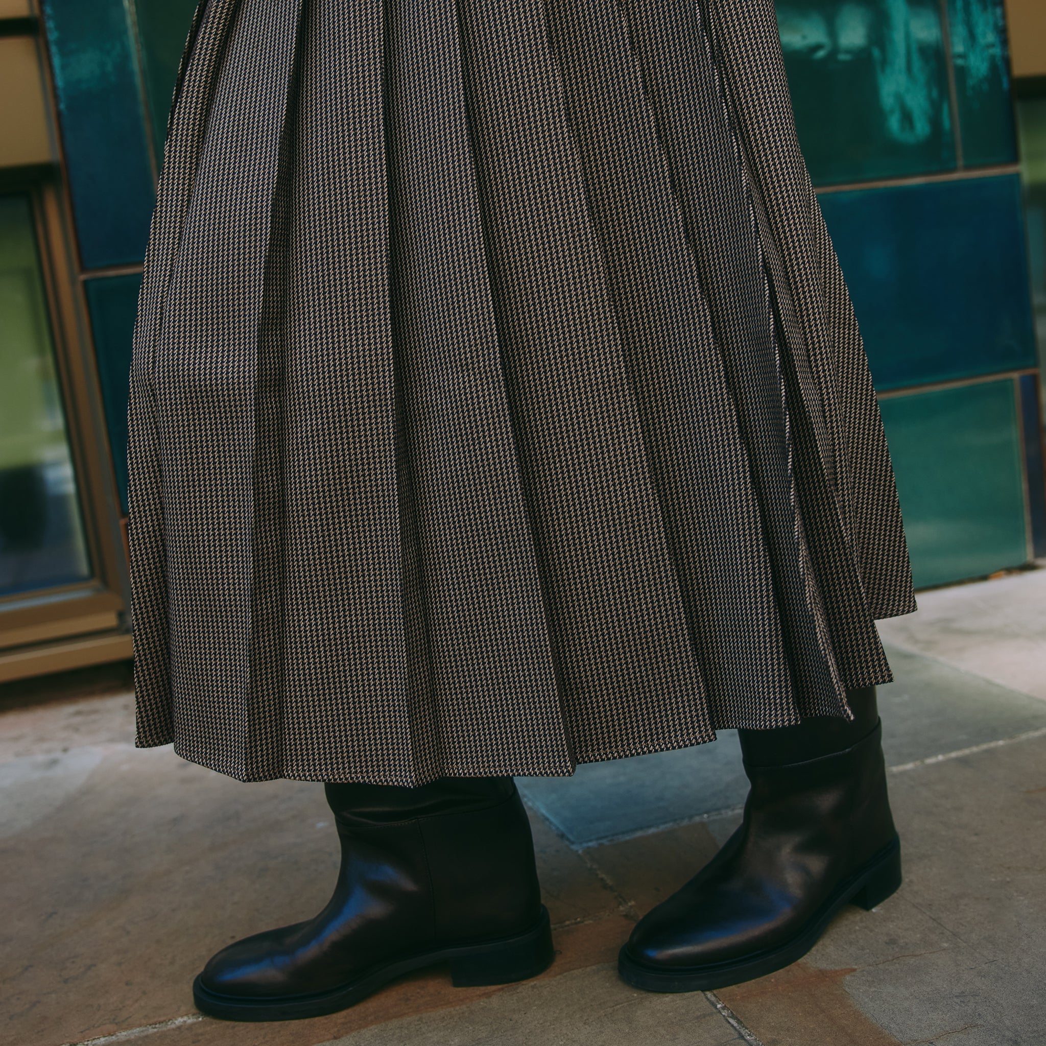 Model wearing houndstooth kilt style pleated skirt with structured pleats and heritage check fabric, an essential autumn wardrobe piece.