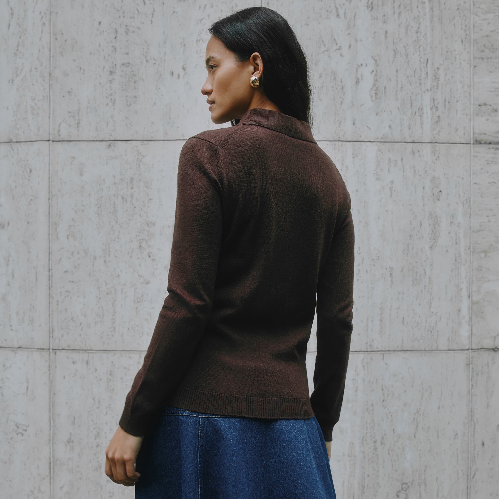 Chocolate knit polo with long sleeves, button placket, and collared neckline in luxe organic cotton blend.