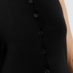 Model wearing black sleeveless cardigan styled with casual layering, showcasing the knit vest's cutaway hem and sleeveless gilet look.