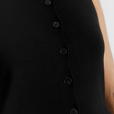 Model wearing black sleeveless cardigan styled with casual layering, showcasing the knit vest's cutaway hem and sleeveless gilet look.
