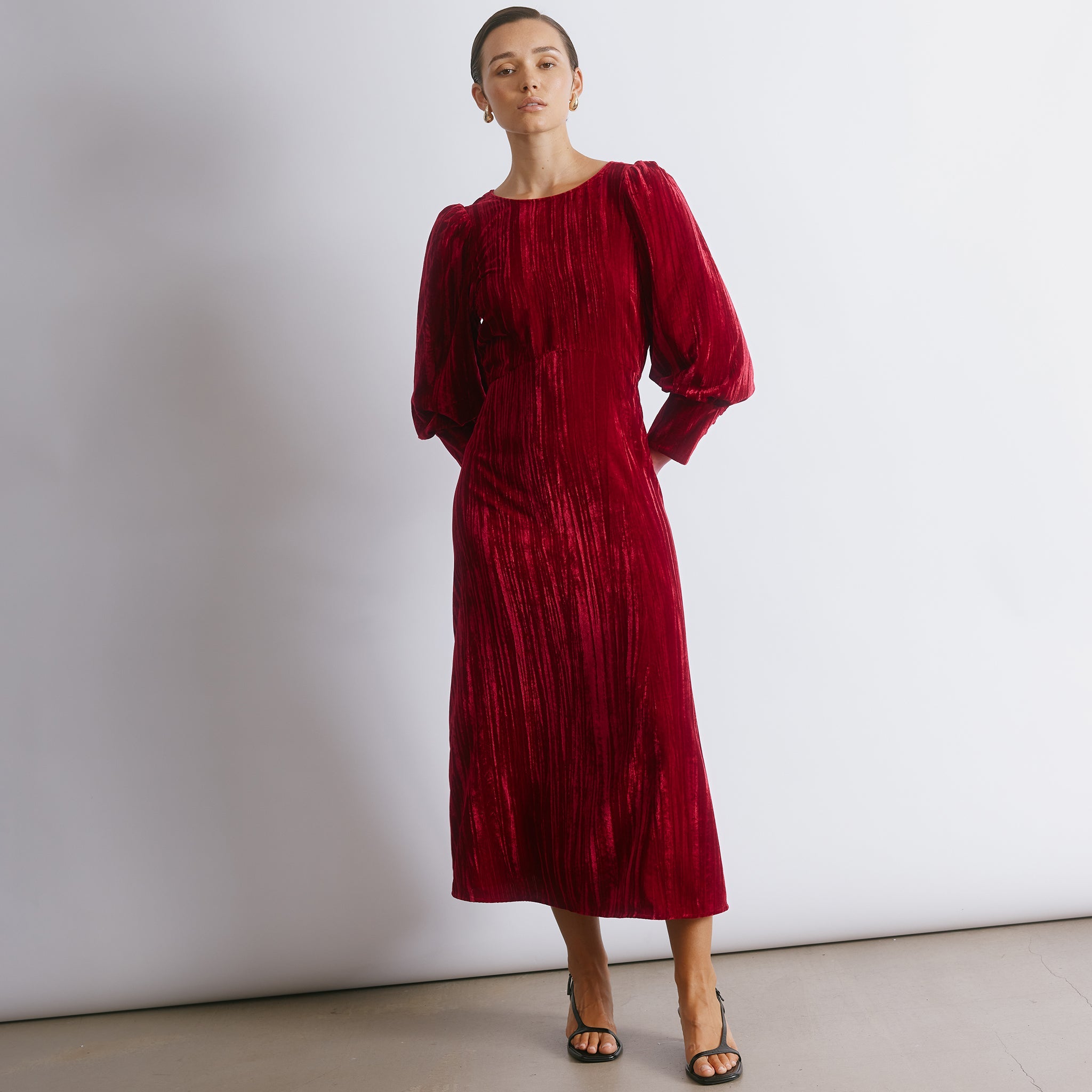 Statement red velvet dress featuring soft draping and a timeless silhouette for winter occasionwear.  