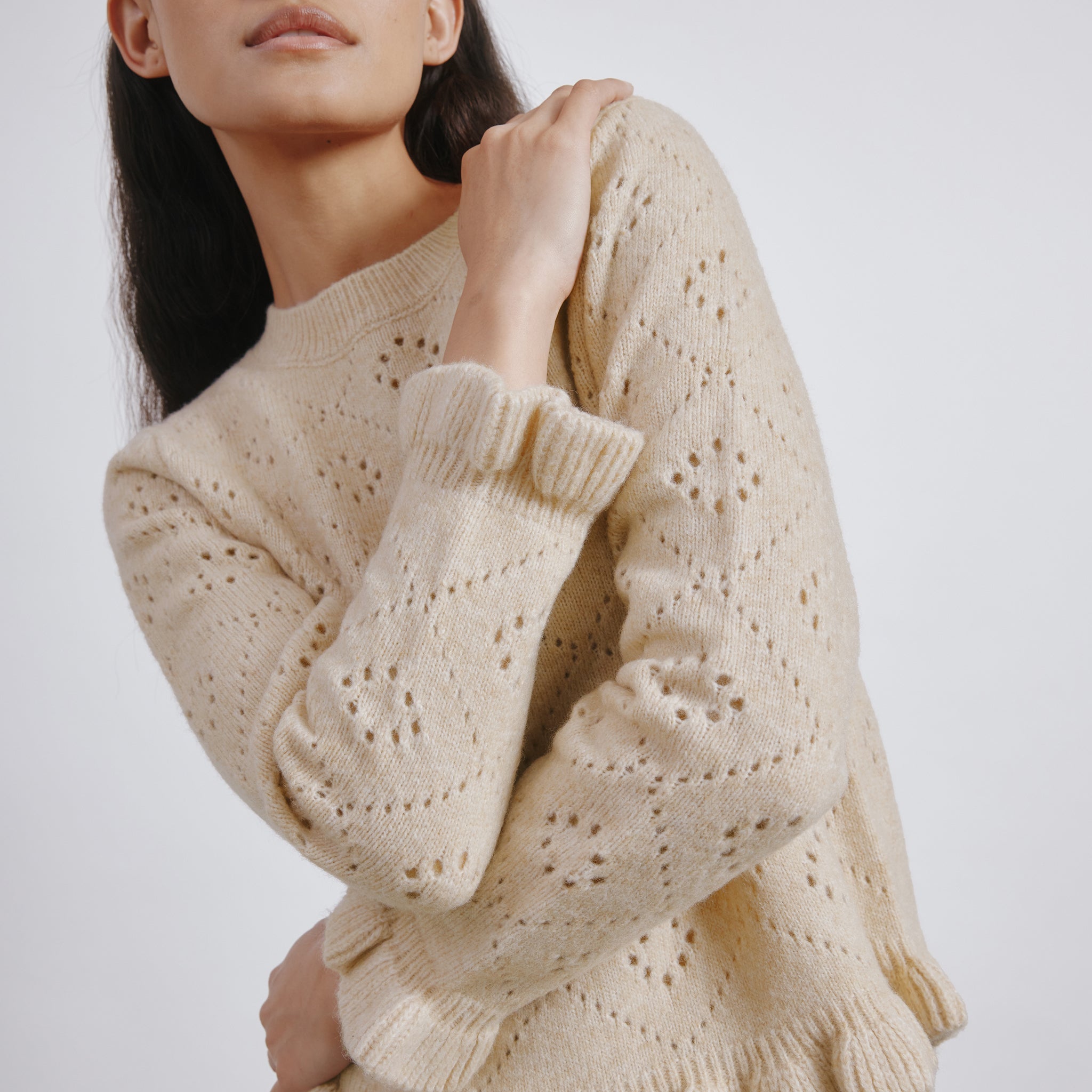 Feminine wool jumper featuring ruffle neckline and delicate knit texture  