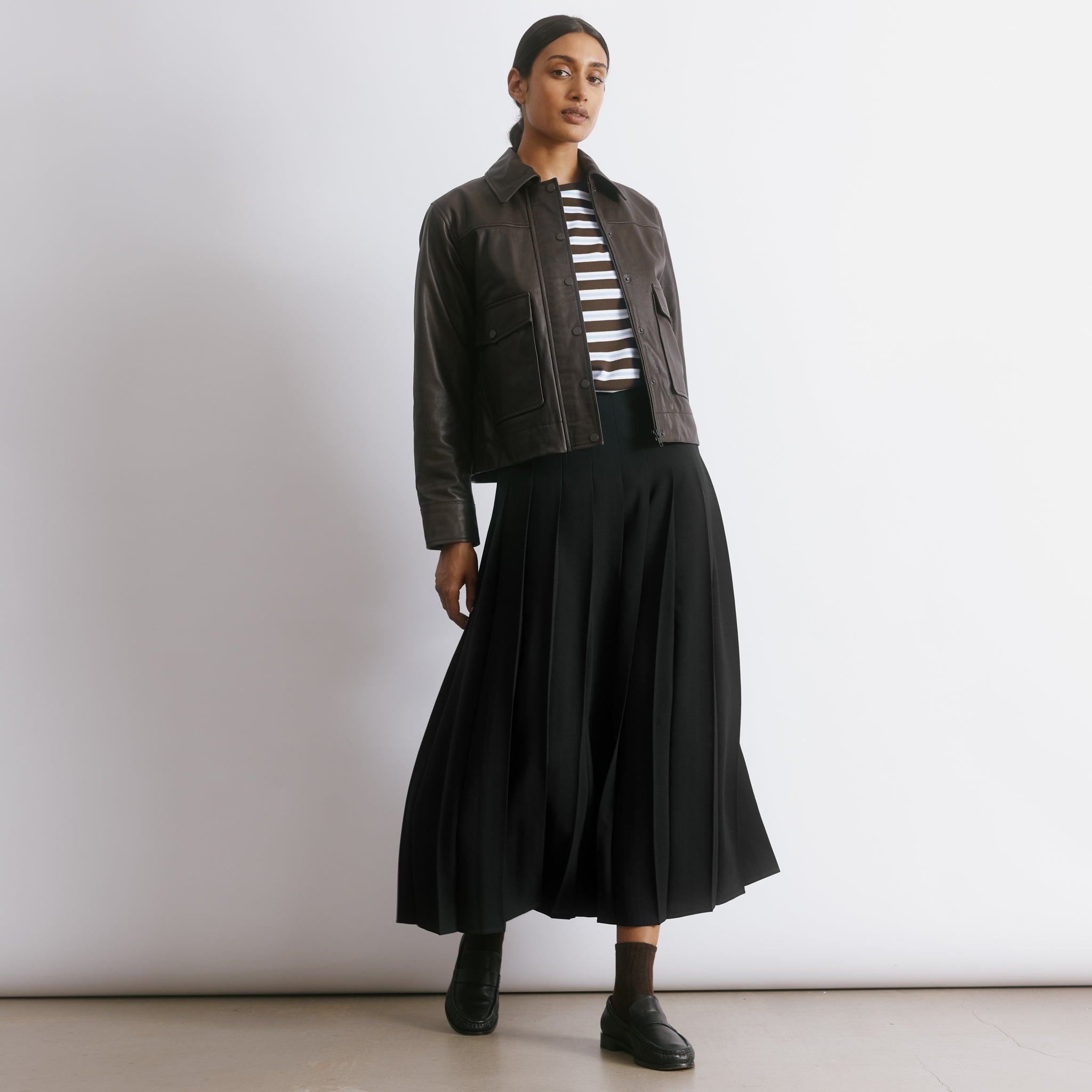 Recycled polyester black skirt featuring classic pleats and a versatile midi length for everyday elegance.  