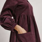 side view of burgundy baby cord dress with sustainable fabric and casual fit  