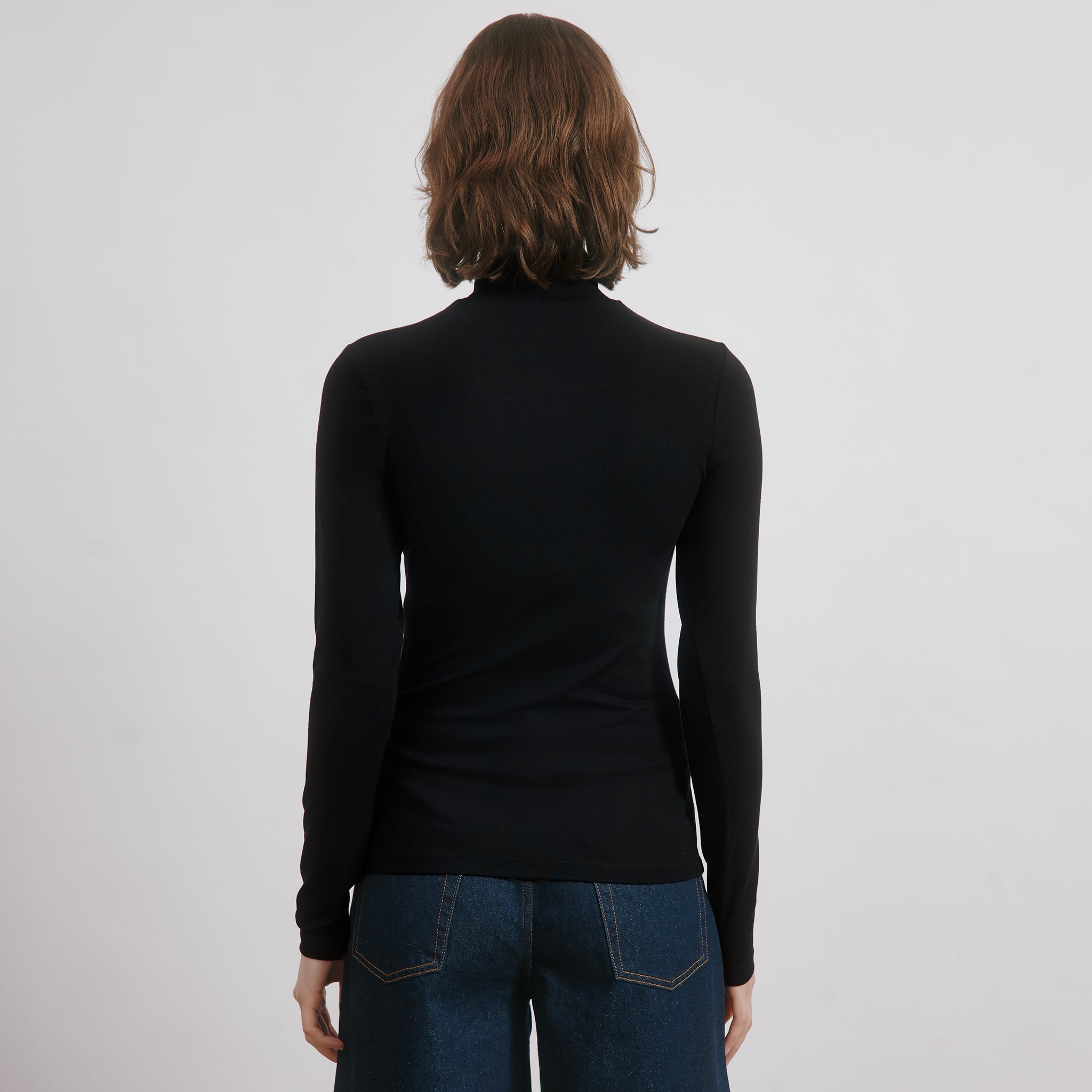 Long sleeve layering top in black slim fit jersey, classic roll neck style, perfect minimalist winter staple with organic cotton jersey fabric, sustainable and ethically made turtleneck. 