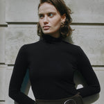 Slim fit black jersey top with long sleeves and classic roll neck, made from organic cotton, a versatile layering piece for sustainable, conscious wardrobes. 