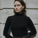 Slim fit black jersey top with long sleeves and classic roll neck, made from organic cotton, a versatile layering piece for sustainable, conscious wardrobes. 