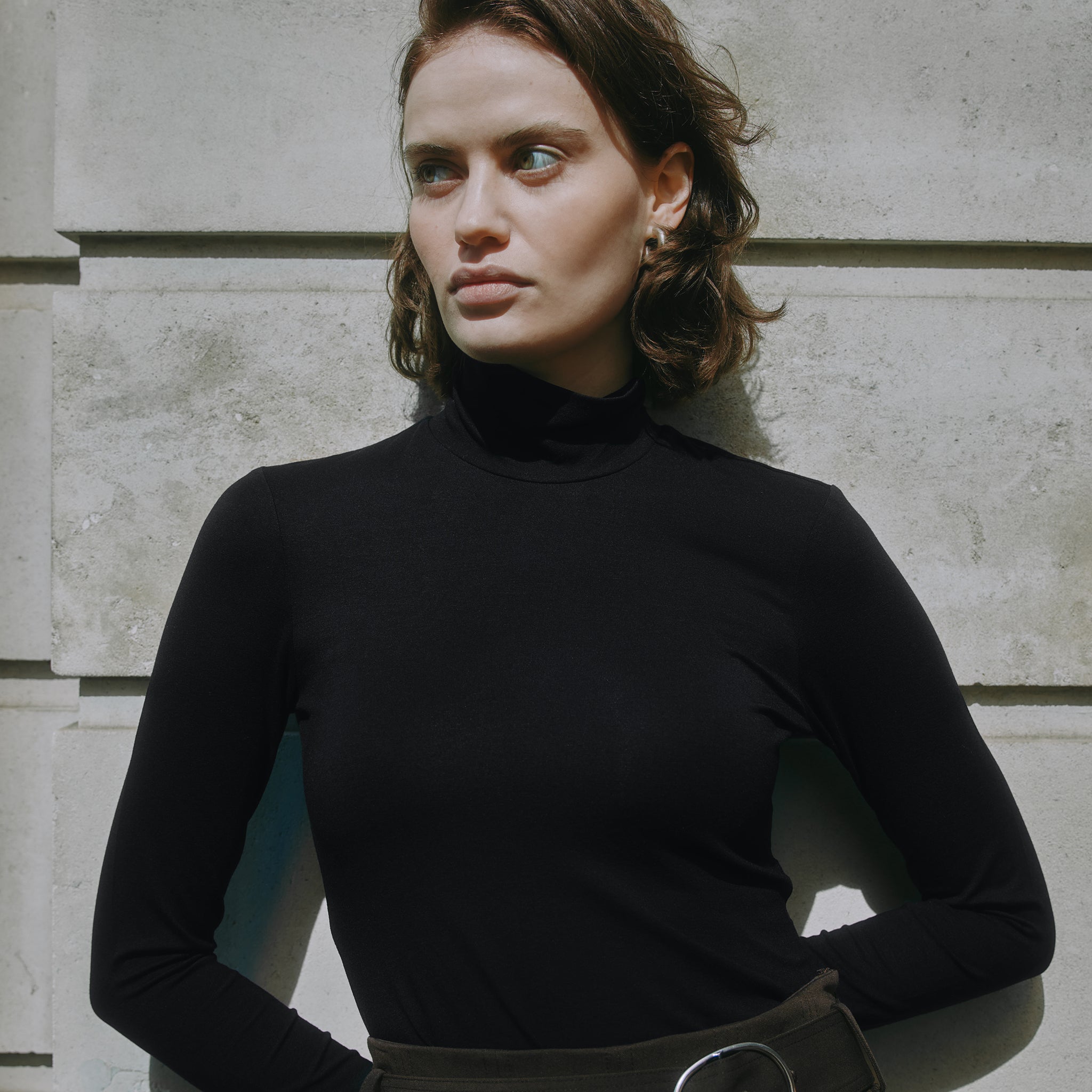 Slim fit black jersey top with long sleeves and classic roll neck, made from organic cotton, a versatile layering piece for sustainable, conscious wardrobes. 