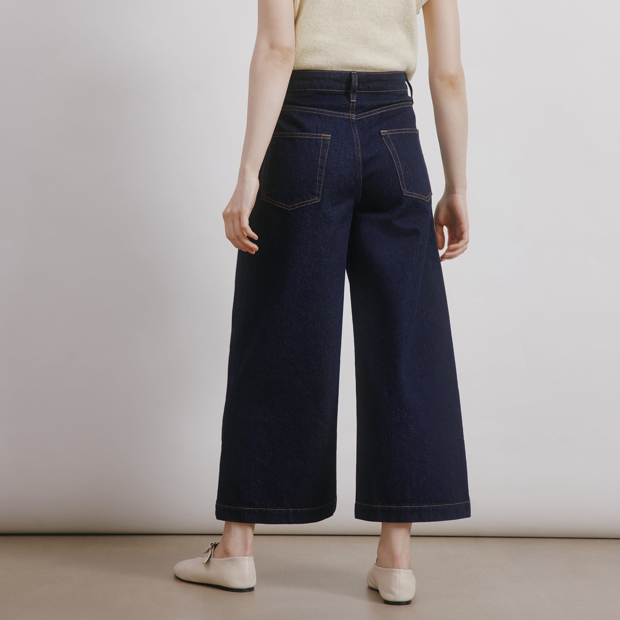 Woman wearing dark indigo wide-leg cropped denim culottes with a relaxed fit and casual 5-pocket design, styled for everyday wear with sustainable and ethically made organic cotton fabric.