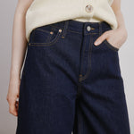 Close-up of dark indigo denim culottes showing contrast stitching and classic 5-pocket styling, highlighting sustainable and eco-conscious craftsmanship in organic cotton.
