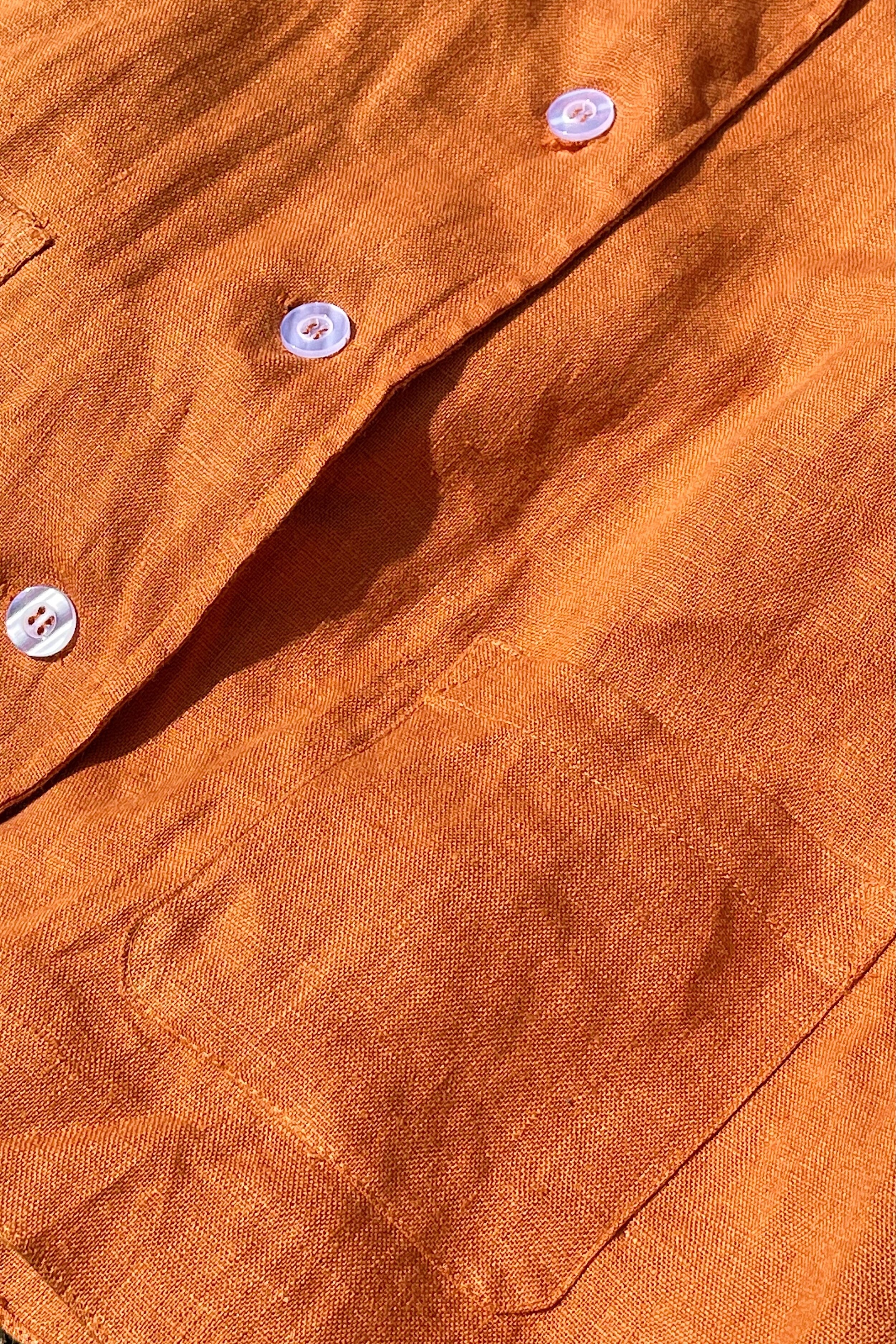 Woman wearing a short sleeve linen button up shirt with frill sleeves and high waisted linen shorts.