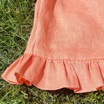 Woman wearing a short sleeve linen button up shirt with frill sleeves and matching high waisted shorts.