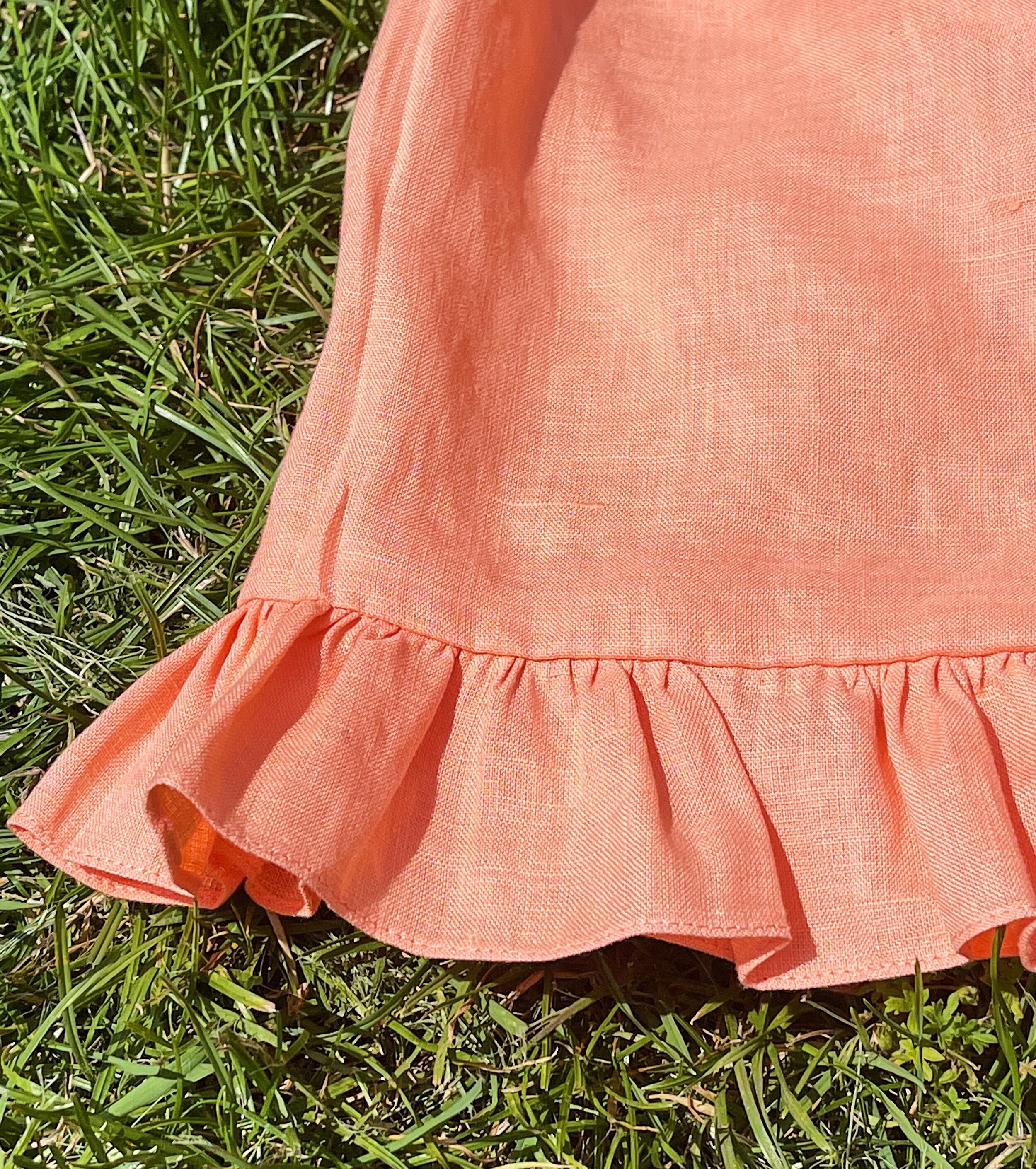 Woman wearing a short sleeve linen button up shirt with frill sleeves and matching high waisted shorts.