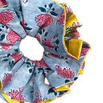 Oversized green floral scrunchie with voluminous fabric folds for a statement hair accessory.
