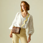 Butter yellow leather handbag with shoulder strap on white background.