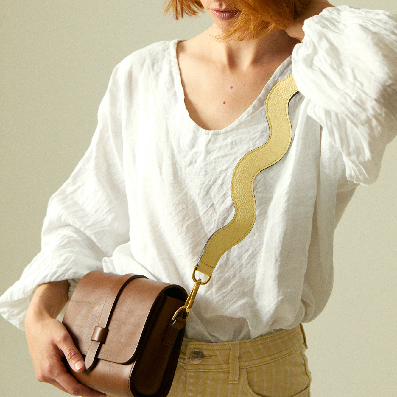 Shoulder strap on butter yellow leather handbag, close-up.