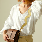 Shoulder strap on butter yellow leather handbag, close-up.