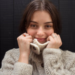 Woman wearing a beige knitted cardigan against a dark wooden background