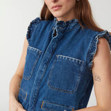 Woman wearing a blue denim waistcoat/ vest with our signature white stitch detailing, two large patch pockets, and a frill collar against a white background