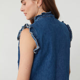 woman wearing a blue denim vest/ waistcoat with our signature white stitch detailing, two large patch pockets, and a frill collar against a white background