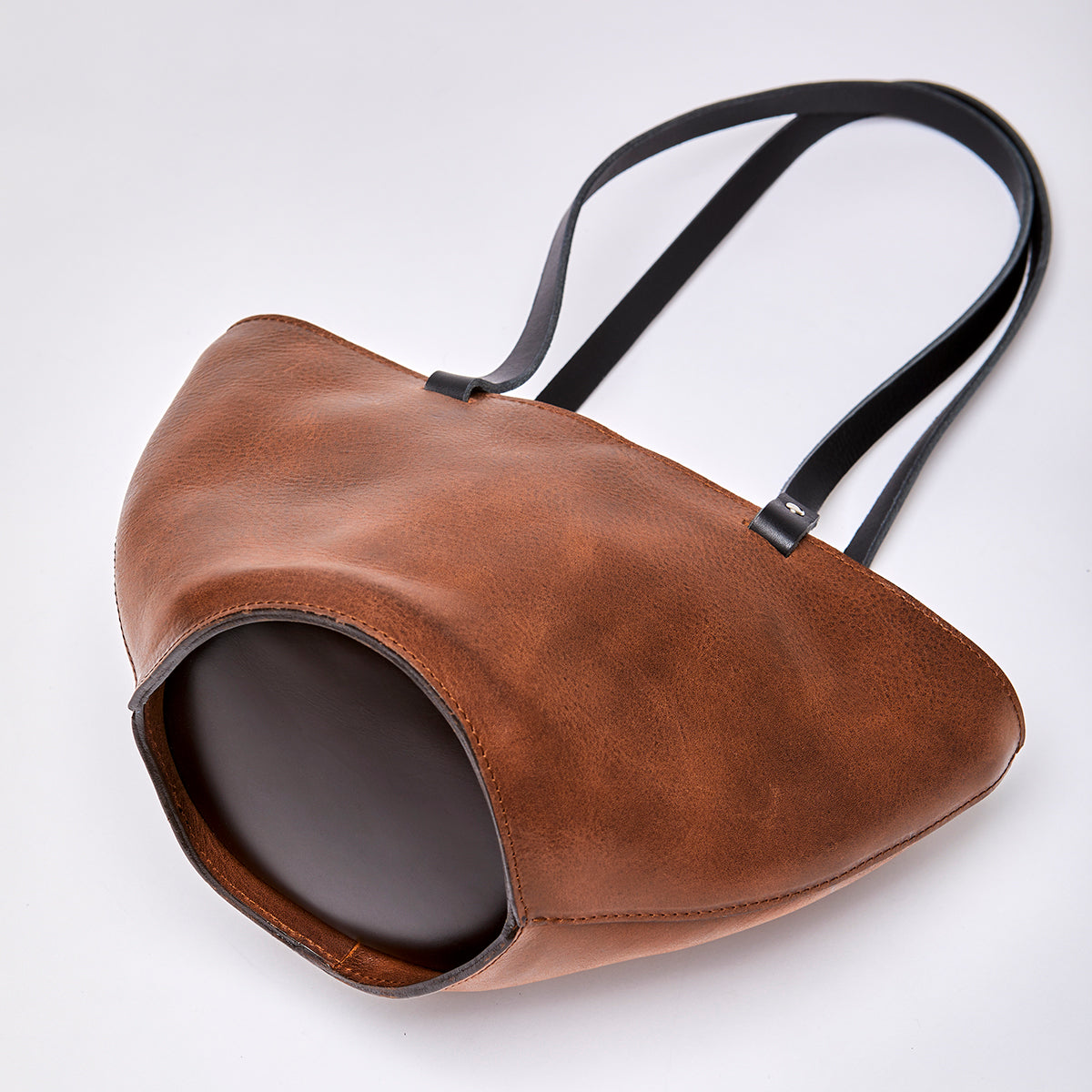 Brown leather handbag featuring gold hardware, made from high-quality upcycled leather