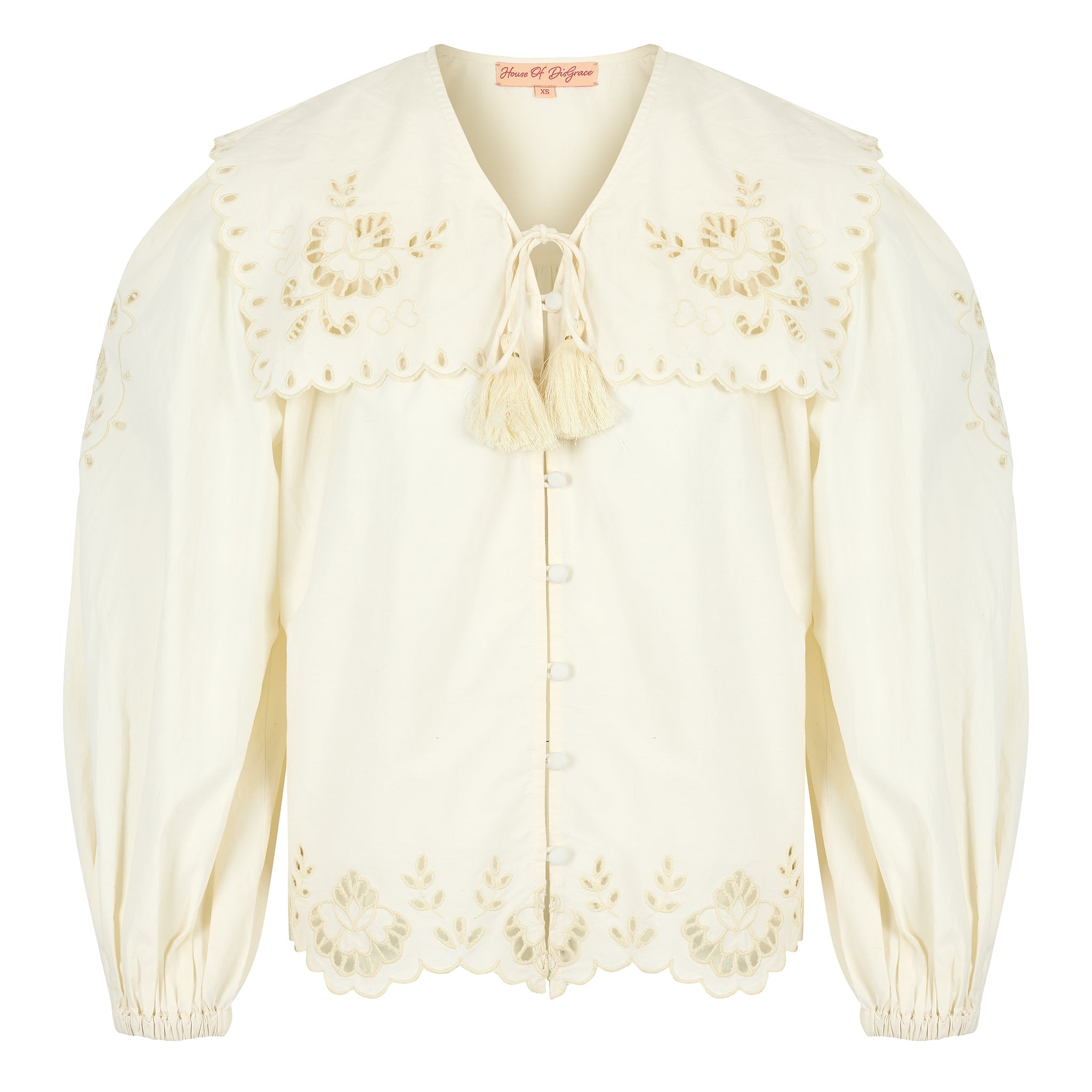 Close-up of scalloped edge on a button up white blouse with balloon sleeves and tie neck.