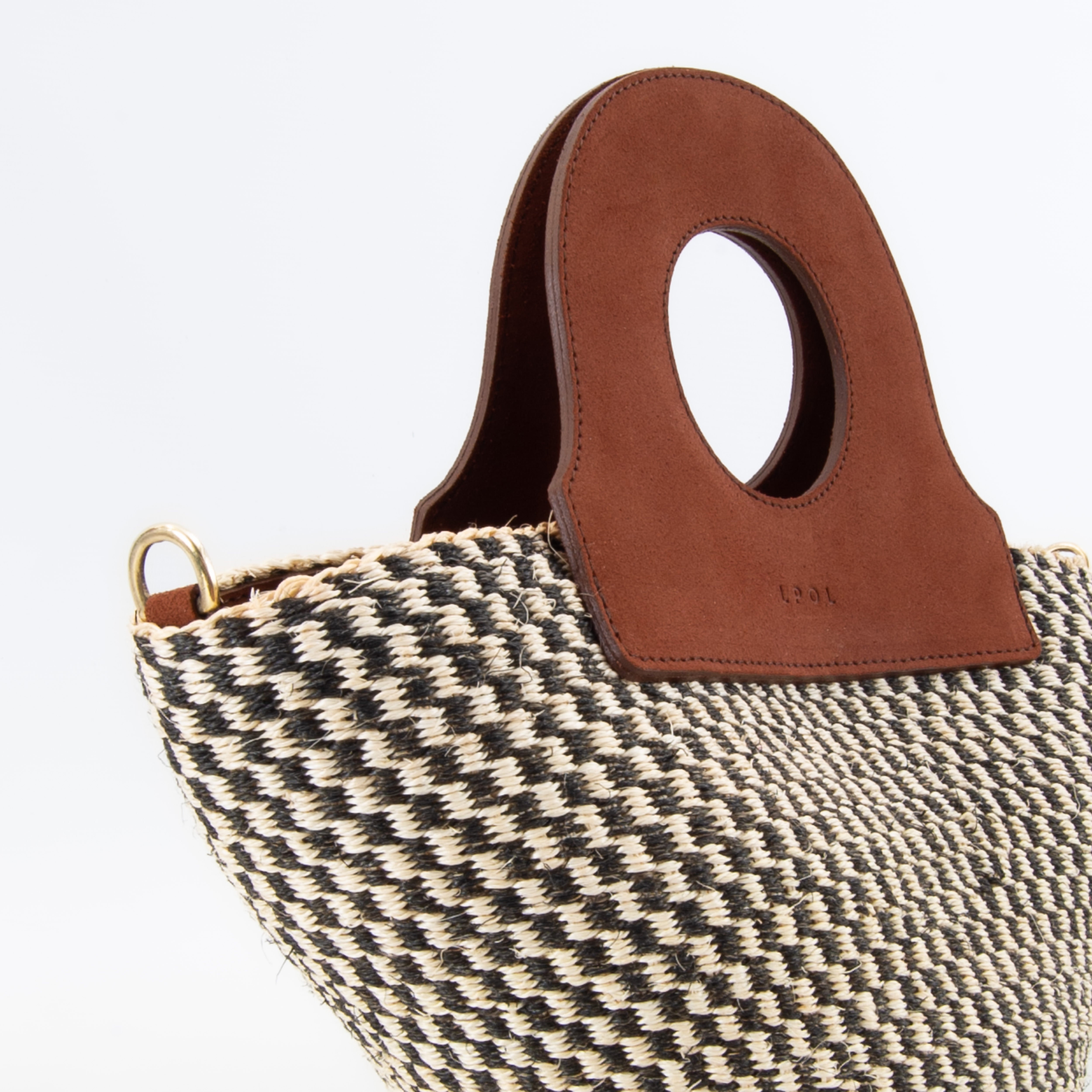 Basket bag resting on wooden surface, showcasing upcycled leather accents.